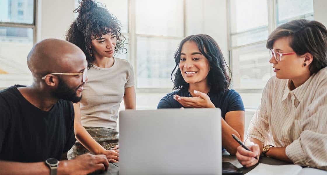 L'équipe de gestion de paie est assise autour de la table de travail. 4 personnes parlent des logiciels de paie.